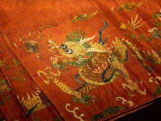 Close-up of an ornate dragon embroidery on red silk fabric showcasing traditional art.