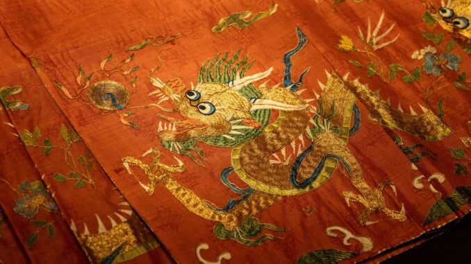 Close-up of an ornate dragon embroidery on red silk fabric showcasing traditional art.